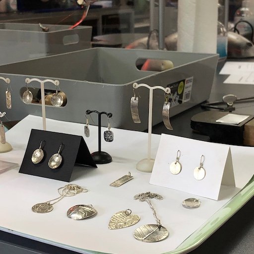 Silver jewellery examples on a tray in the workshop