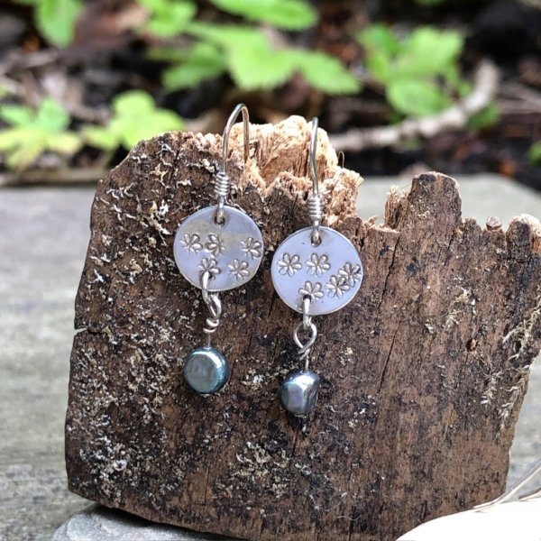 Silver earrings with dangly pearl on tree bark