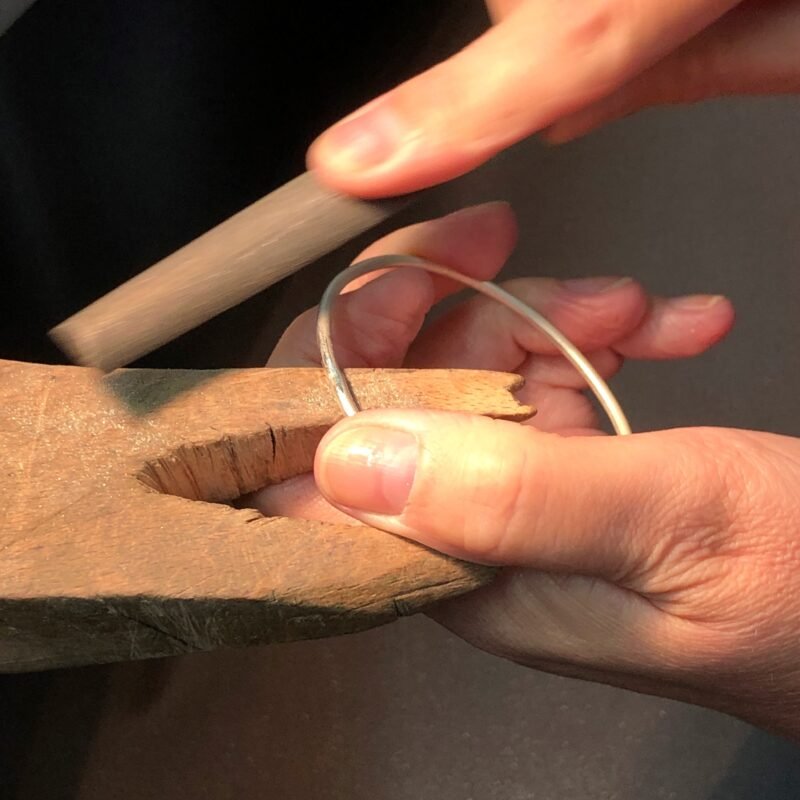 Filing a silver bangle at the benchpeg
