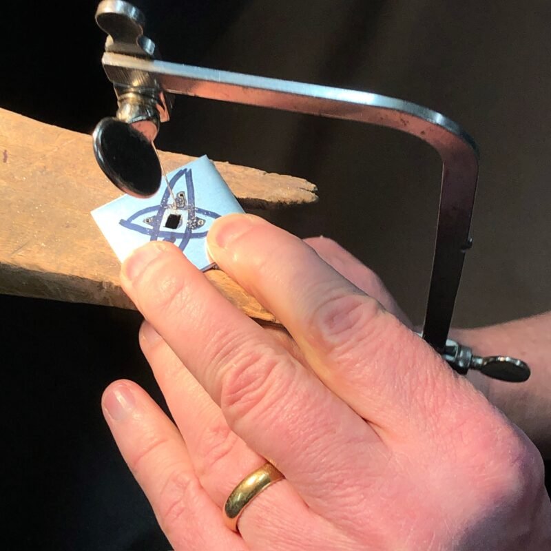 Saw piercing a charm at the benchpeg
