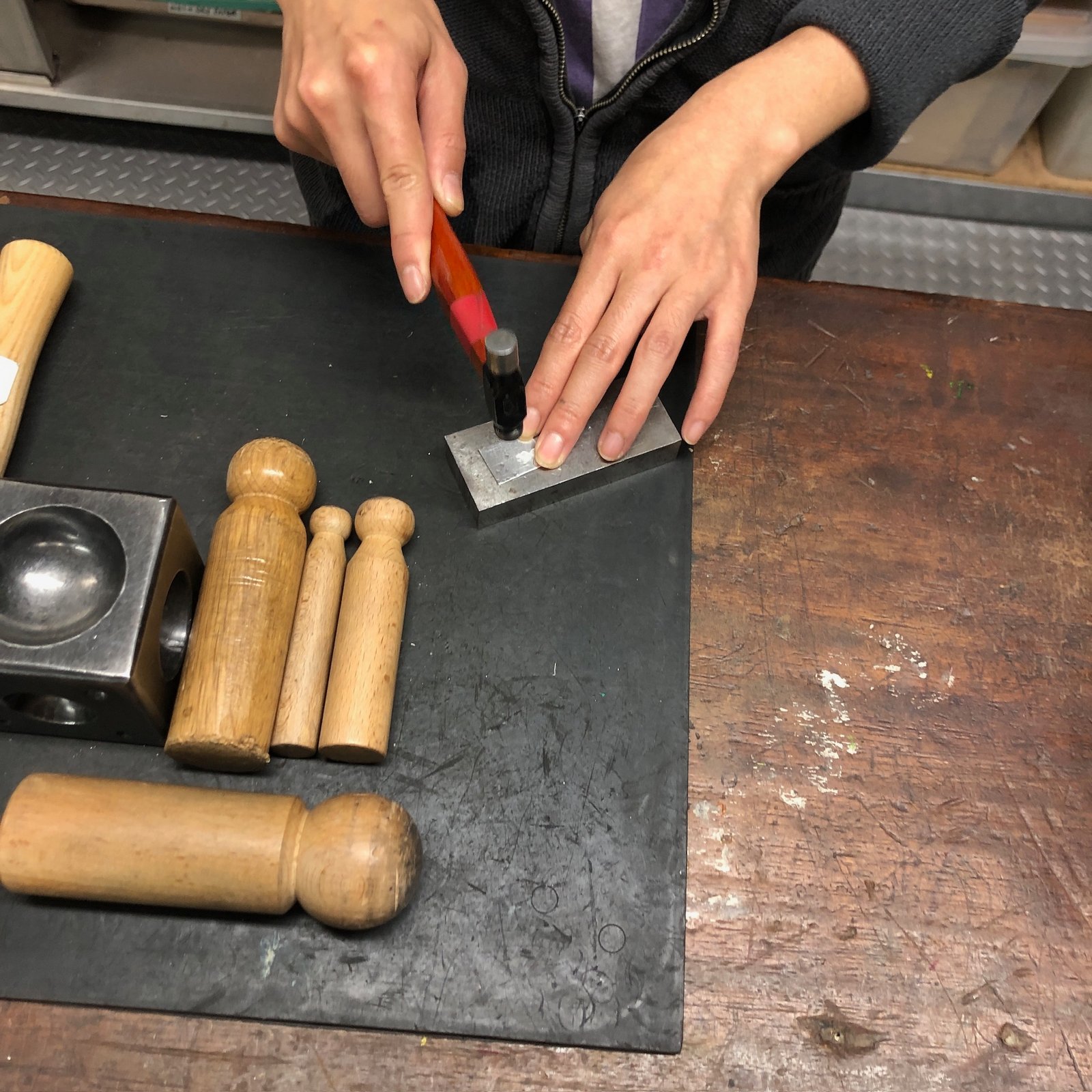 Student hammering metal at the workbench