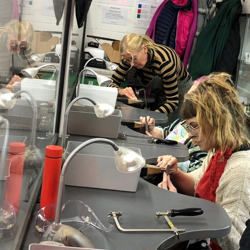 Students at jewellery benches saw piercing and filing