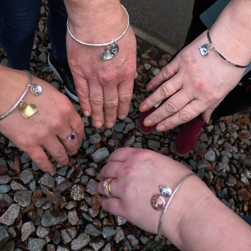 Silver charm bangles being worn