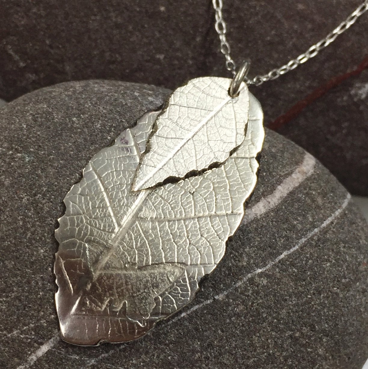Double layer silver leaf pendant on stone background