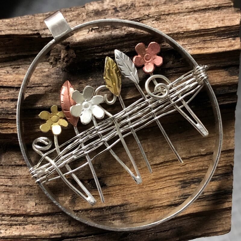 Mixed metal flowers inside a ring pendant.