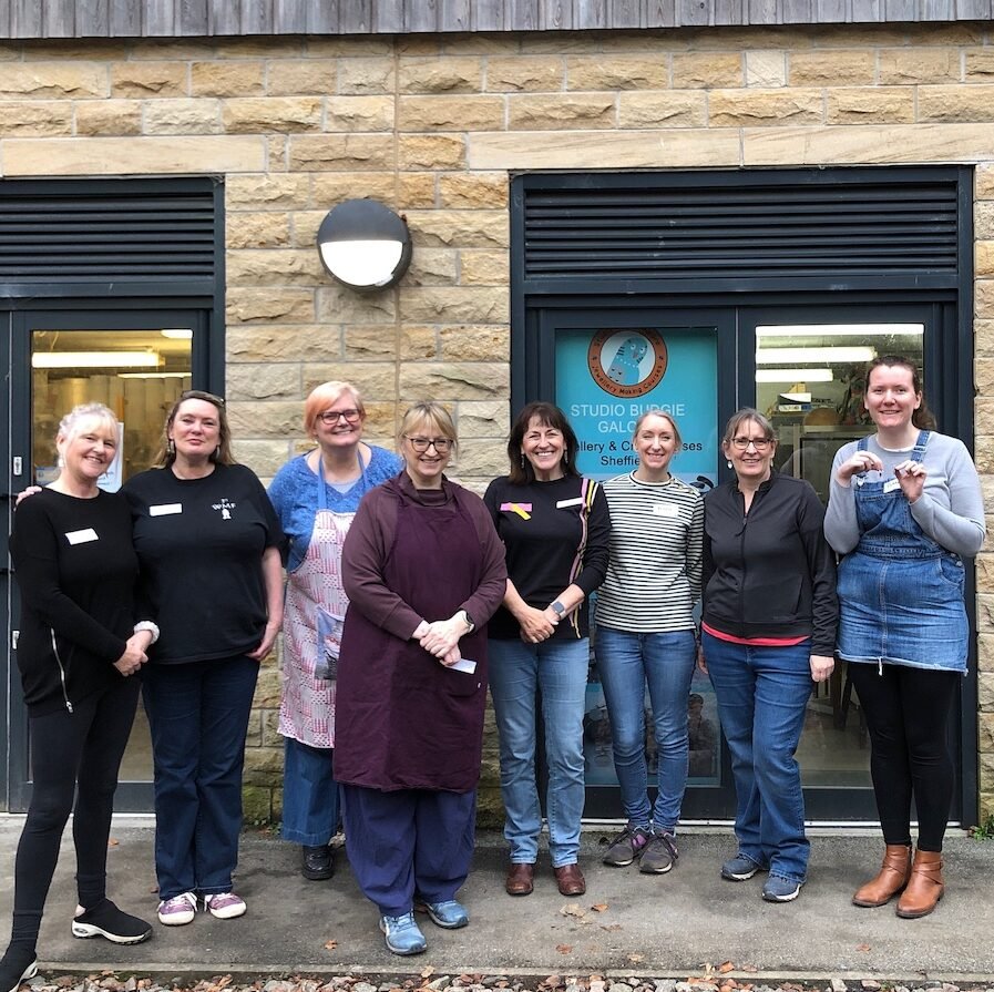 Happy faces wearing their handmade silver earrings outside the workshop