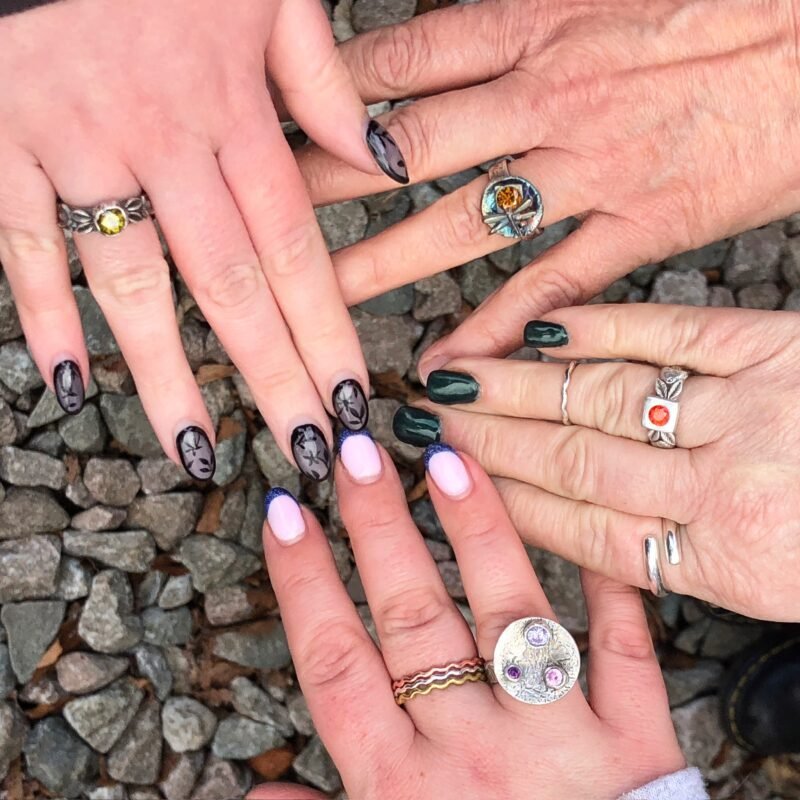 Four hands in a circle wearing finished silver clay rings