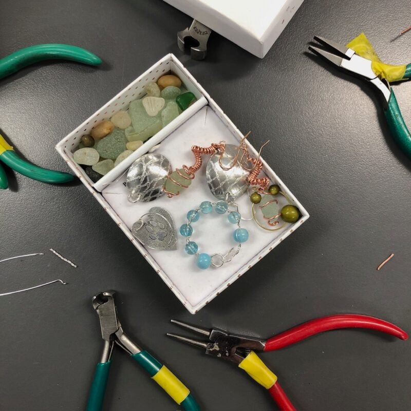 Box of found sea glass and new pieces of jewellery with pliers and wire cutters