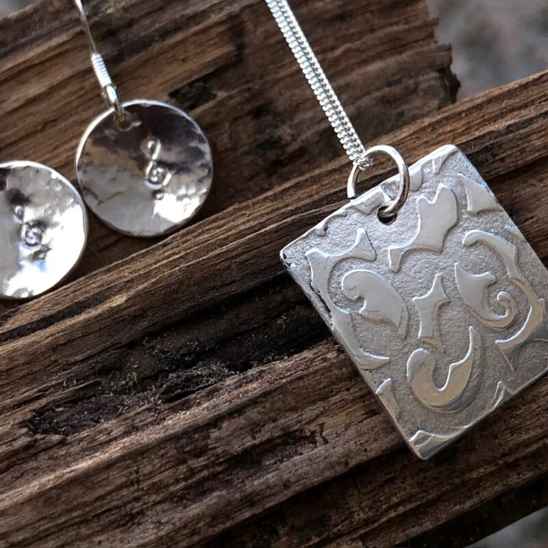 Silver pendant with swirly texture and earrings with musical note stamp