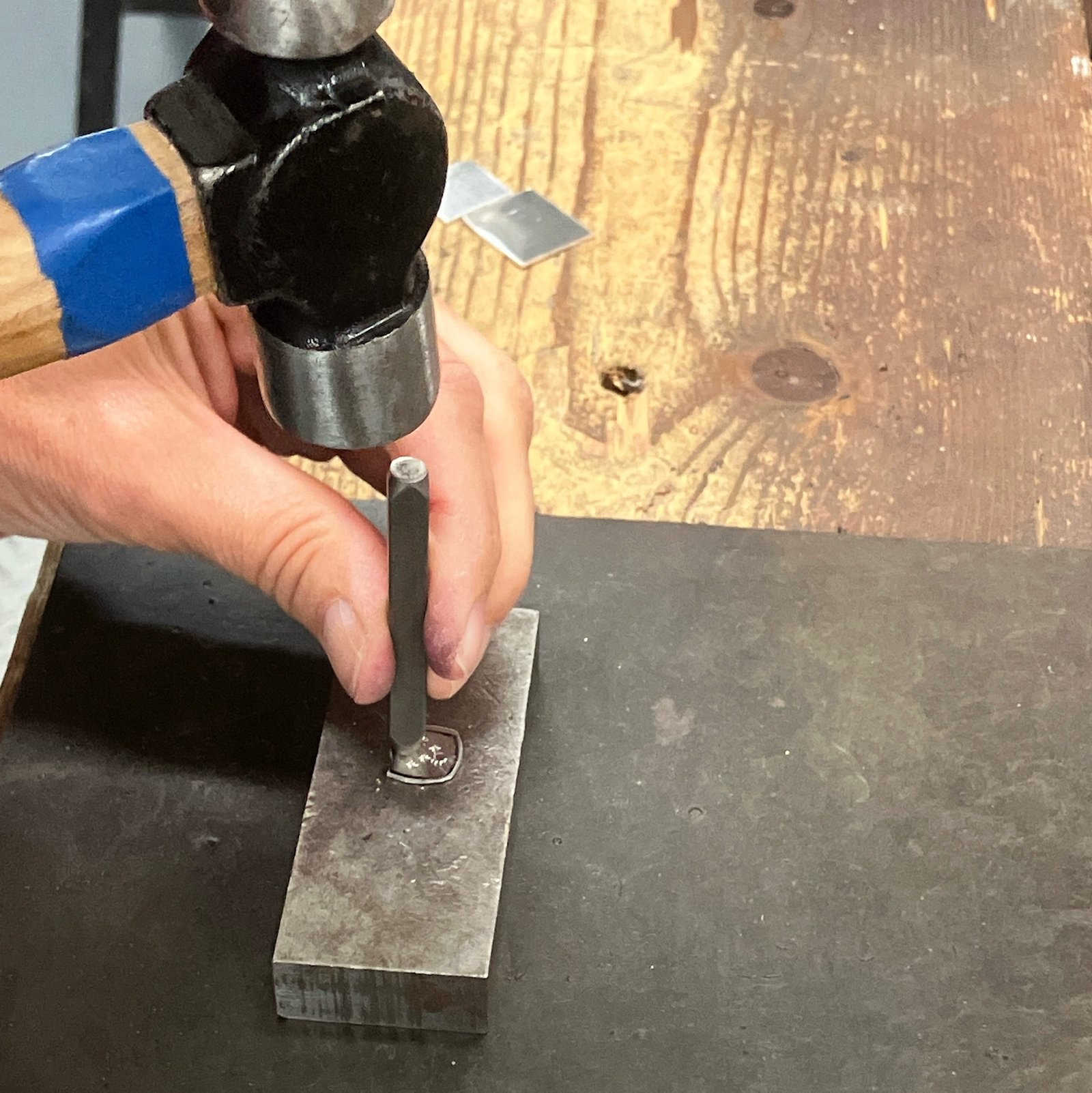 Using a hammer and metal punch to mark the metal