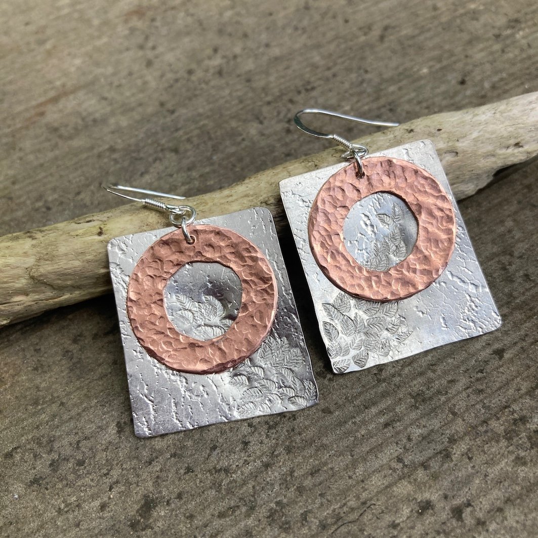 Copper and aluminium earrings inspired by Abbeydale on a wood background